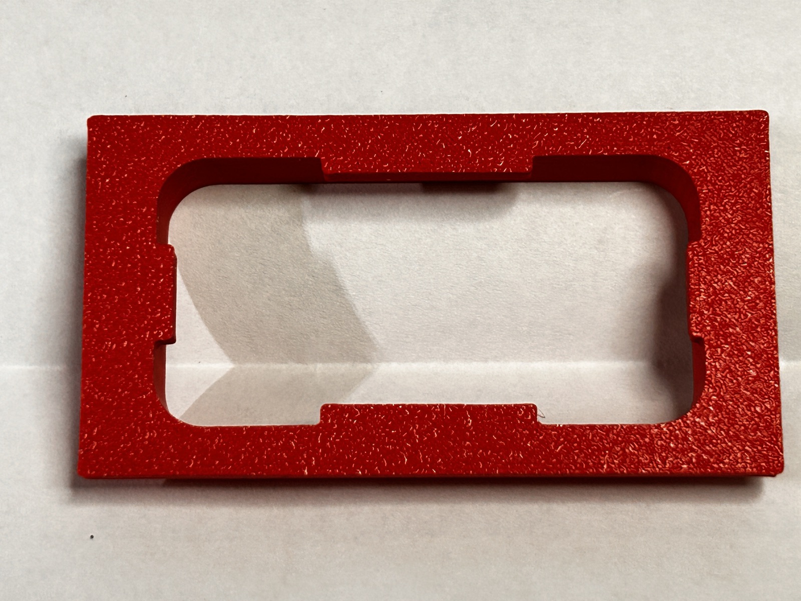 Red 3D-printed mounting jig used to align stickers on the accessory clip