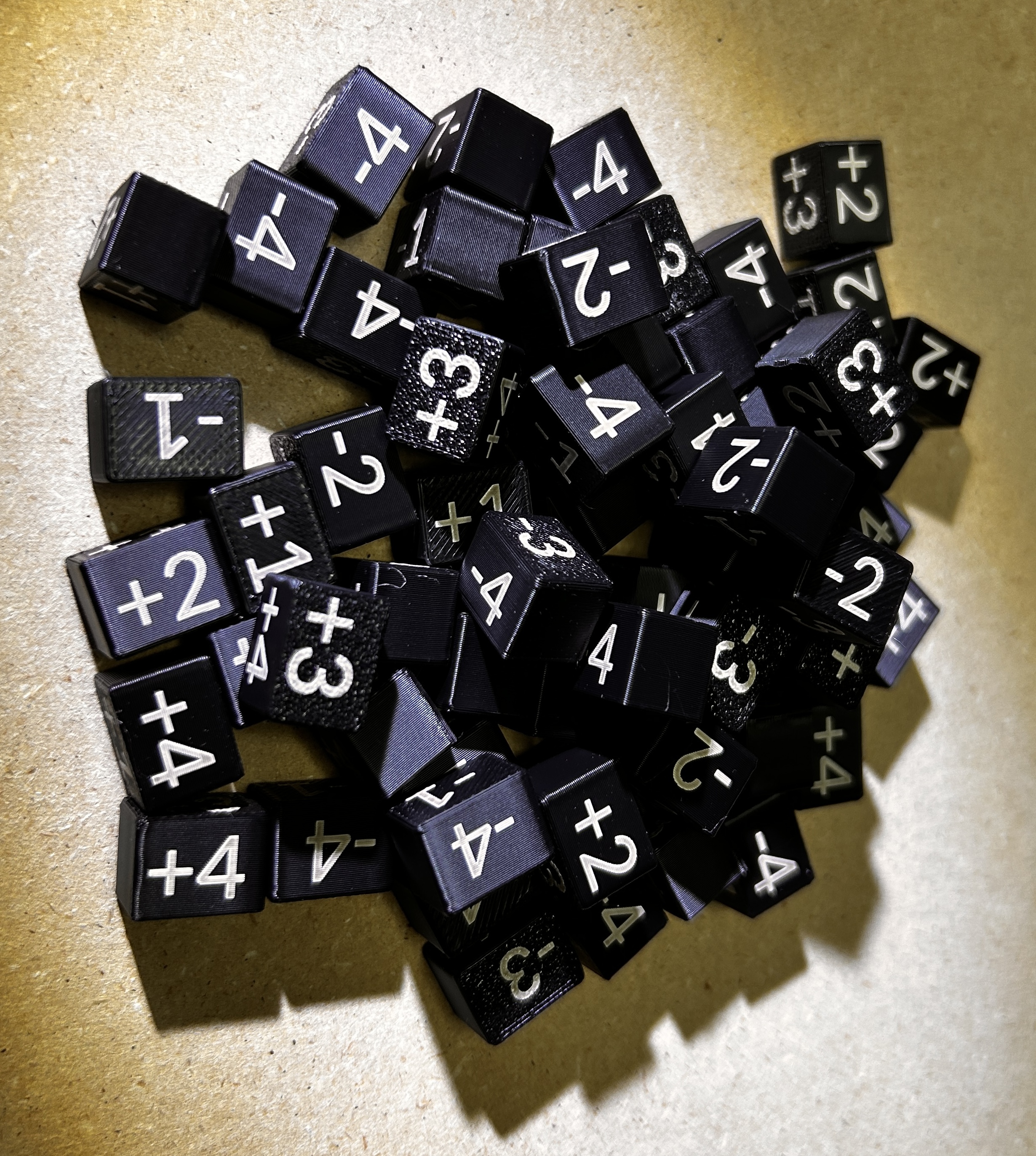 Black 3D-printed Cost Dice with white positive and negative number markings