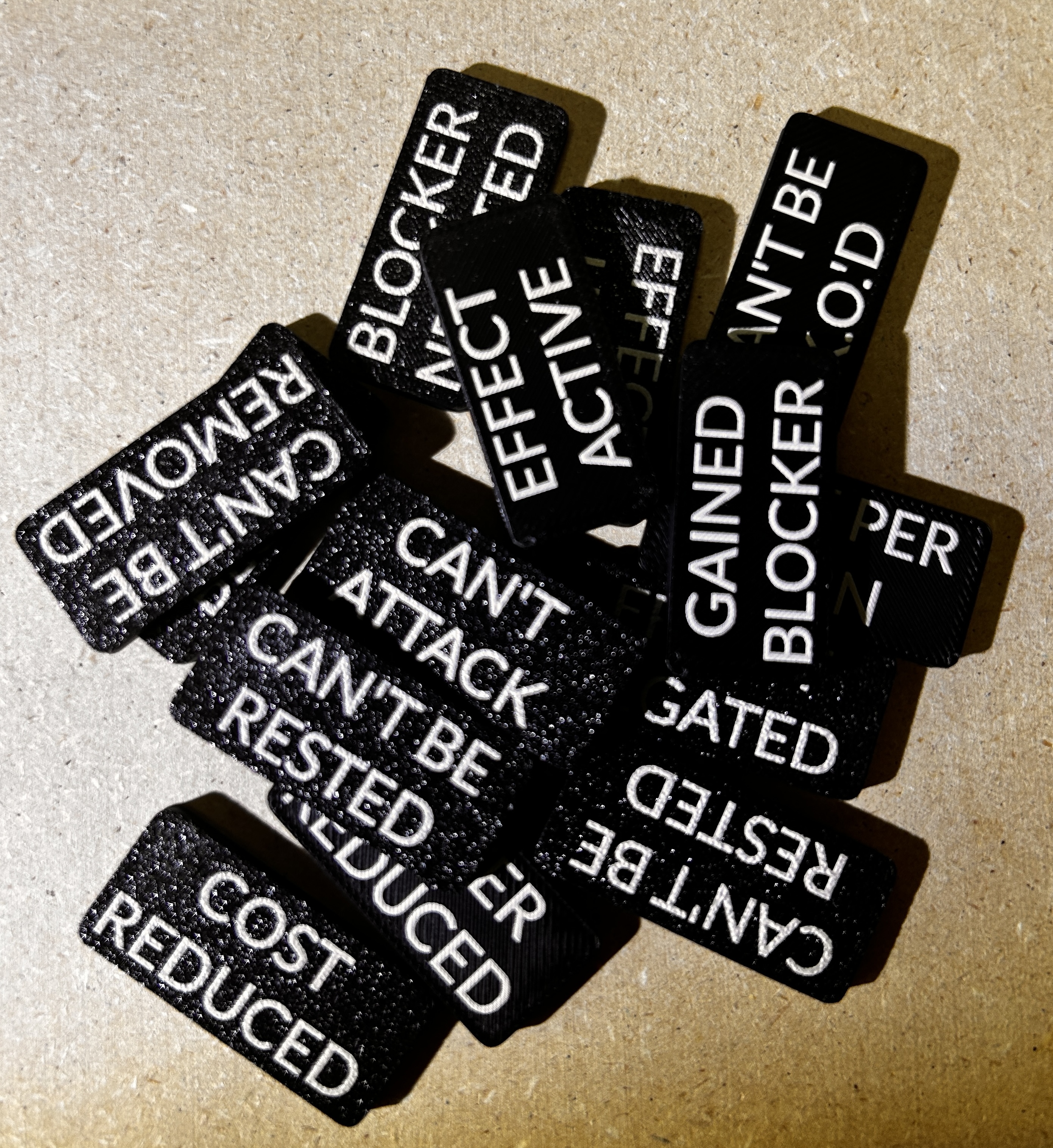 Pile of black double-sided Slim Tokens with white game-status keywords